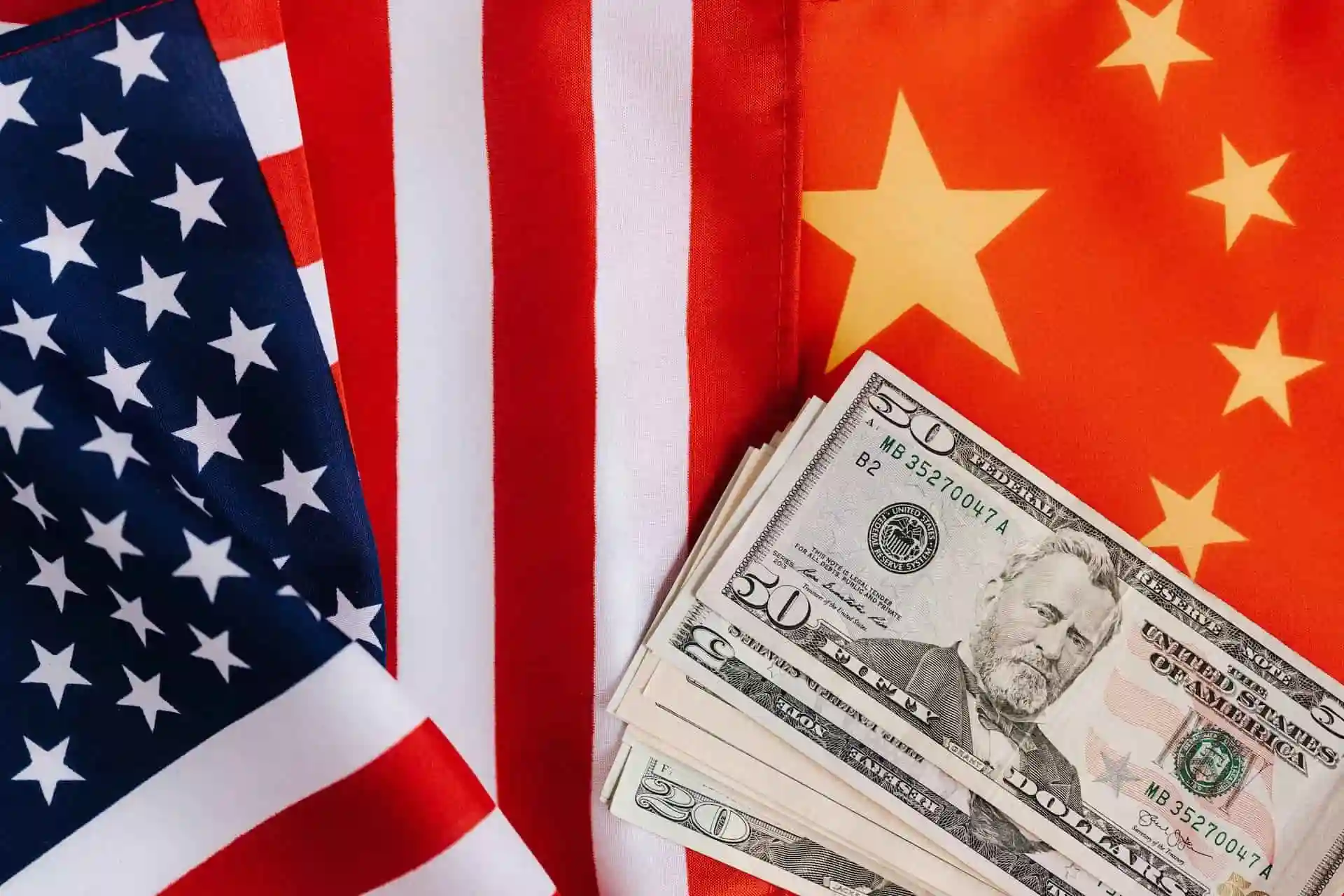 US and Chinese flags with US dollars in between. Several companies in China are now US-sanctioned.